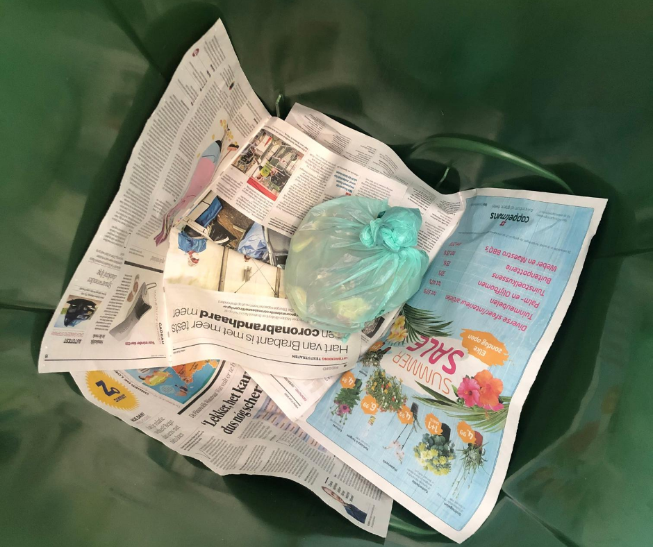 Kranten in groene afvalcontainer