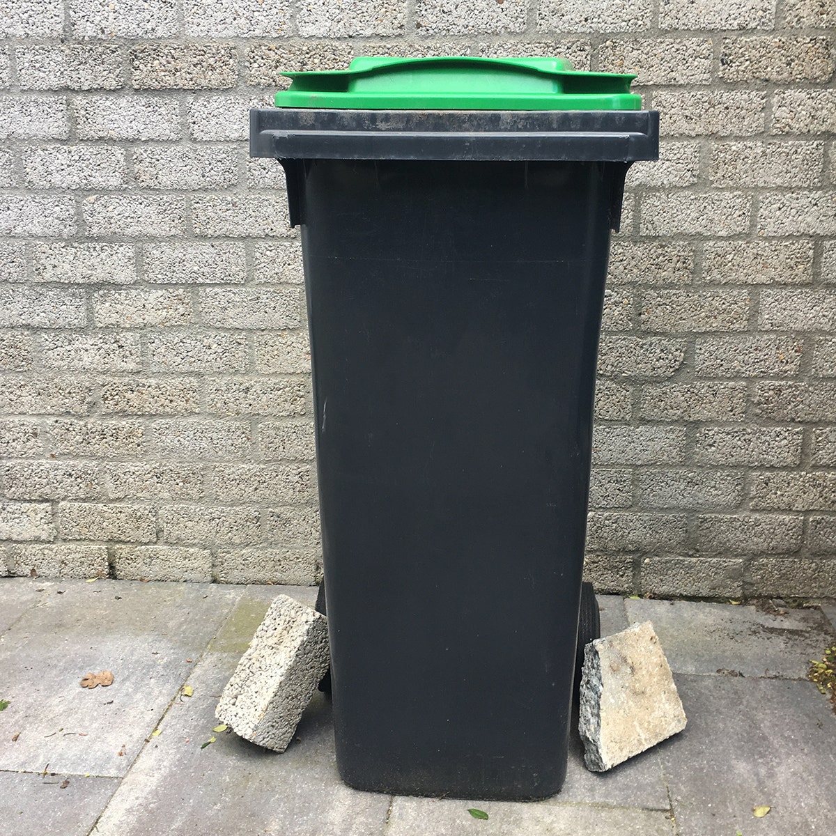 Container verzwaren met stoeptegel - omvallende afvalcontainer