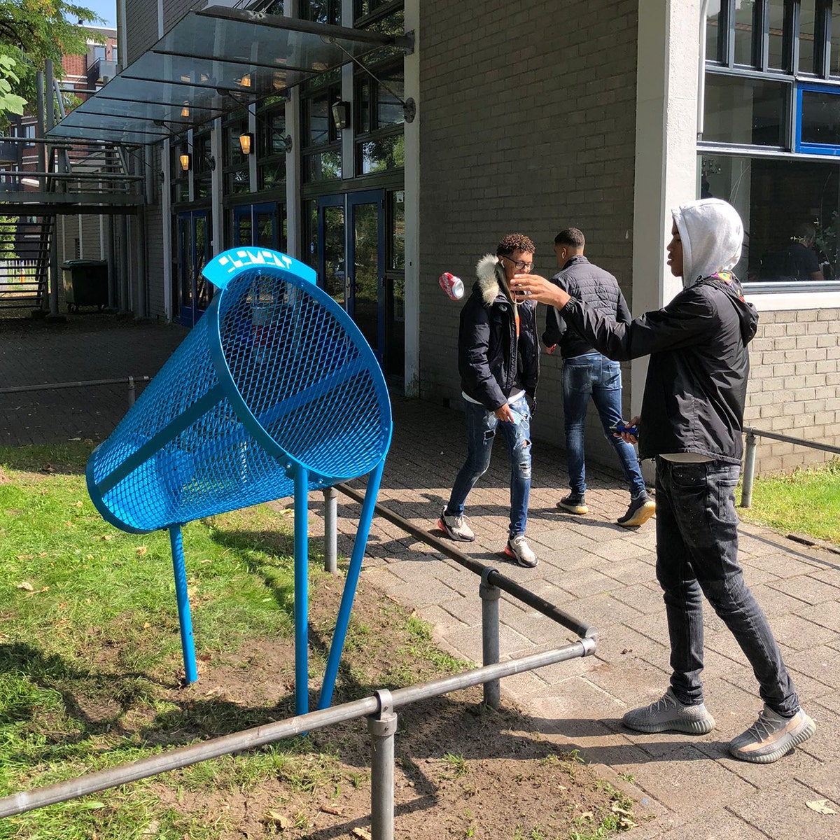 Jongen gooit afval weg in Binswinger buitenafvalbak op het schoolplein