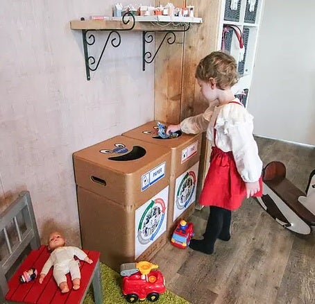 Peuter gooit afval weg in de afvalbox - kartonnen afvalbak