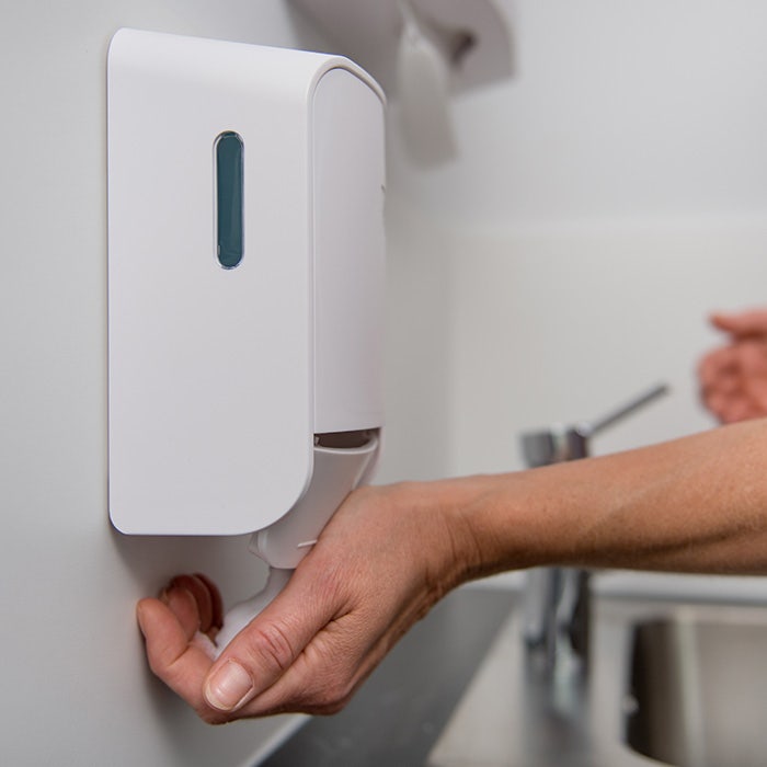 Persoon pakt zeep met een zeepdispenser